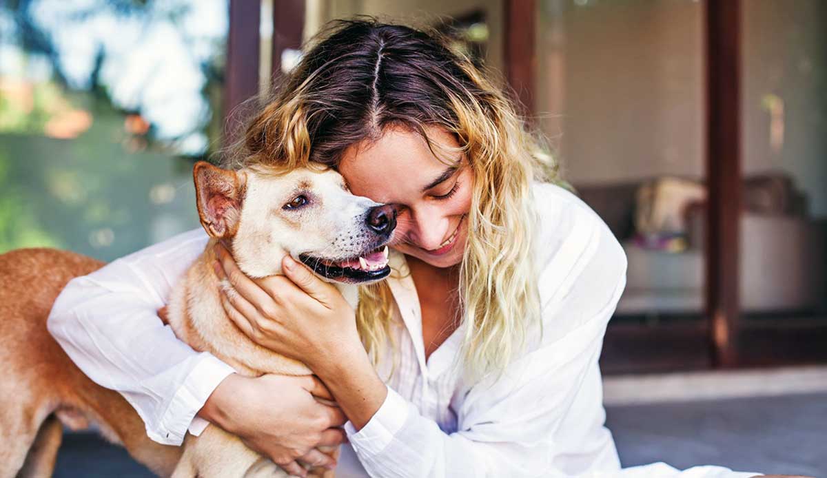 woman hugging small dog
